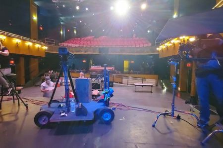 Reverse shot of camera on dolly filming stage performance